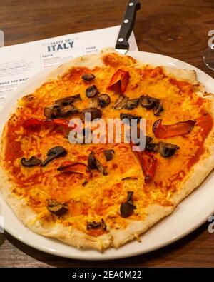 Margherita Vegan Käse und Gemüse auf pflanzlicher Basis, Pilz und Pfeffer Pizza mit dünner Kruste, Bella Italia, italienische Küche, British Chain Restaurant, Casual Dini Stockfoto