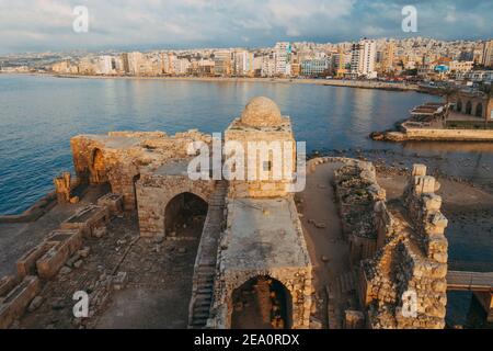 Überreste des alten Sidon Sea Castle in der Hafenstadt Sidon, Libanon. Wohnblöcke säumen die Bucht dahinter Stockfoto