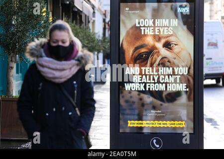 London, Großbritannien. Februar 2021, 02nd. Eine Frau mit einer Gesichtsmaske geht an einem Plakat der Werbekampagne von Covid-19 NHS in London vorbei. Die britische Regierung hat gesagt, dass sie bis Mai 2021 alle über 50s Impfungen machen wird. Kredit: SOPA Images Limited/Alamy Live Nachrichten Stockfoto