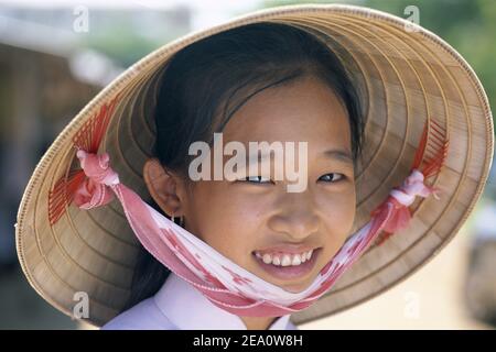 Asia,Vietnam, Ho Chi Minh City aka Saigon,Portrait of Smiling Young Vietnamese Girl traging traditional Conical hat Stockfoto