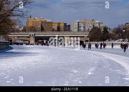 Ottawa, Ontario, Kanada - 6. Februar 2021: Eisläufer genießen den Rideau Canal Skateway, wo er unter der Pretoria Bridge in Ottawa läuft. Stockfoto