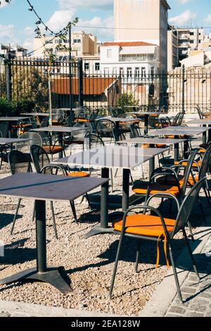 Orangefarbene Kissen auf Metallstühlen auf der leeren Terrasse Stockfoto