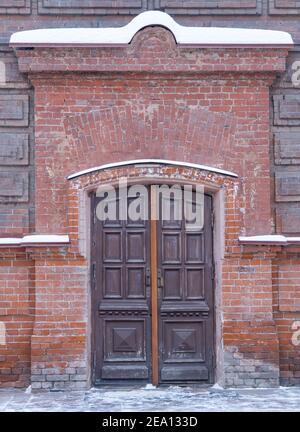 Alte hölzerne Eingangstüren. Massive Tür in einem Ziegelgebäude. Stockfoto