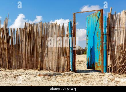 Bambuszaunung mit einer alten rostigen Metalltür Stockfoto