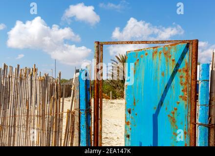 Bambuszaunung mit einer alten rostigen Metalltür Stockfoto