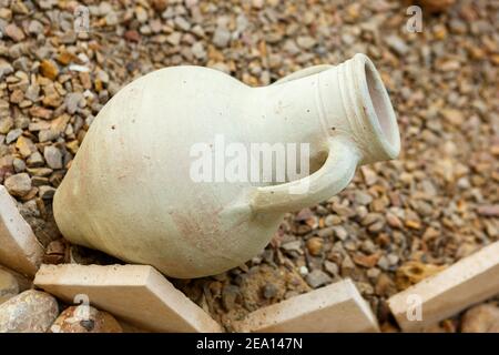 Ein alter Steingut-Wasserkrug sitzt auf einem kleinen Schutthaufen. Nahaufnahme. Stockfoto