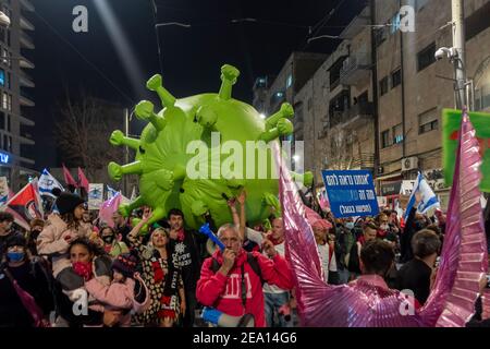 Demonstranten tragen ein riesiges Modell eines Coronavirus, während sie auf ihrem Weg zum offiziellen Wohnsitz des Premierministers durch die Innenstadt Jerusalems marschieren, während sie eine Demonstration zum Rücktritt von Benjamin Netanjahu aufrufen, unter Berufung auf den Umgang seiner Regierung mit der Coronavirus-Pandemie und die anhaltenden rechtlichen Probleme in Jerusalem, Israel. Stockfoto