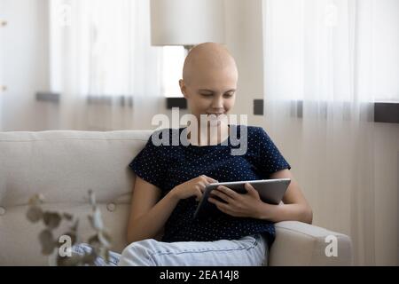 Lächelnde Frau mit Krebs entspannen Sie sich mit Tablet Stockfoto