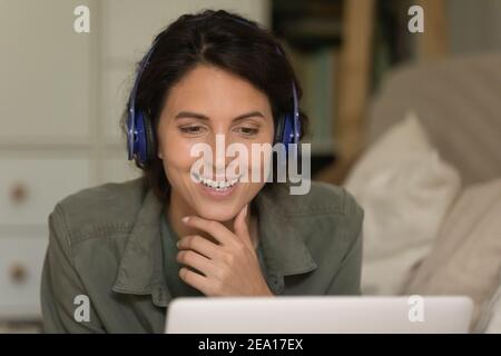 Glückliche Millennial Frau in Kopfhörer mit Laptop Stockfoto