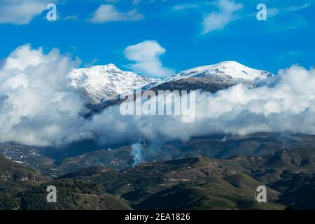 Landschaft des südlichen Abhangs der Sierra Nevada, mit dem Gipfel des Pico del Caballo bedeckt mit Schnee und von niedrigen Wolken begrenzt. Stockfoto