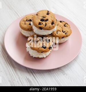 Hausgemachte Schokolade Chip Cookie Ice Cream Sandwich auf einem rosa Teller auf einem weißen Holztisch, Seitenansicht. Nahaufnahme. Stockfoto