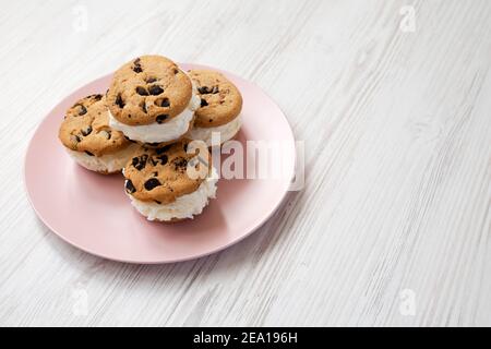Hausgemachte Schokolade Chip Cookie Ice Cream Sandwich auf einem rosa Teller auf einem weißen Holzhintergrund, Seitenansicht. Leerzeichen für Text. Stockfoto