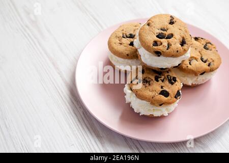 Hausgemachte Schokolade Chip Cookie Ice Cream Sandwich auf einem rosa Teller auf einem weißen Holzhintergrund, Seitenansicht. Speicherplatz kopieren. Stockfoto