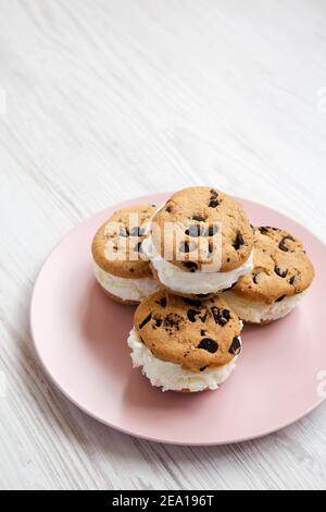 Hausgemachte Schokolade Chip Cookie Ice Cream Sandwich auf einem rosa Teller auf einer weißen Holzfläche, Seitenansicht. Speicherplatz kopieren. Stockfoto