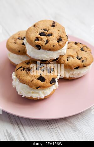 Hausgemachte Schokolade Chip Cookie Ice Cream Sandwich auf einem rosa Teller auf einem weißen Holzhintergrund, Seitenansicht. Stockfoto