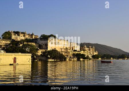 Sehen Sie sich den Stadtpalast von Udaipur an, der sich in einem Wasser des Pichola-Sees widerspiegelt. Sonnenuntergangszeit. Stockfoto