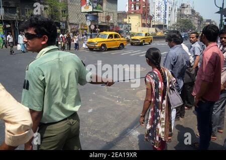 Kolkata, Indien - März, 2014: Menschen überqueren Straße auf Fußgänger. Indischer Stadtverkehr. Kalkutta Bürger warten auf dem Fußgängerüberweg. Mann mit Seil Stockfoto