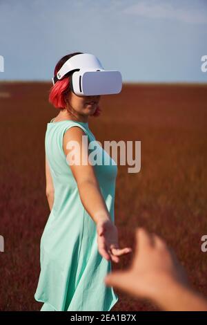 Frau geht in die virtuelle Realität mit Virtual-Reality-Headset. Das Konzept der virtuellen Realität, Simulationen, Verbindung und Kommunikation. Stockfoto