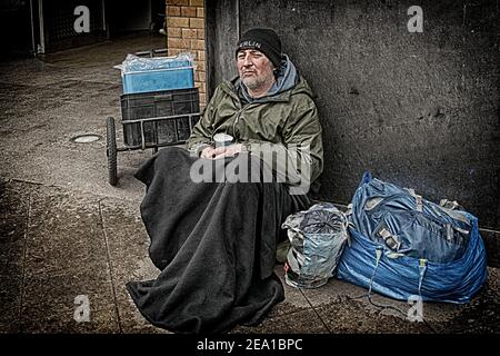 Obdachloser, der auf der Straße sitzt, bittet um Unterstützung Stockfoto