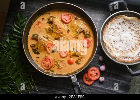 Draufsicht würzige Kerala Stil Fisch Curry Eintopf und Appam Fisch Molee Meen Moilee Indische Küche. Fischcurry mit Kokosmilch rote Chili, Curryblatt, Tomaten. Stockfoto