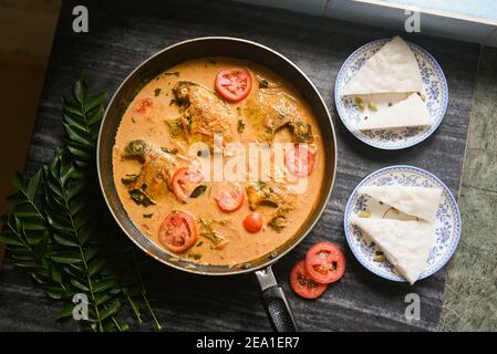 Draufsicht würzige Kerala Stil Fisch Curry Eintopf und Appam Fisch Molee Meen Moilee Indische Küche. Fischcurry mit Kokosmilch rote Chili, Curryblatt, Tomaten. Stockfoto