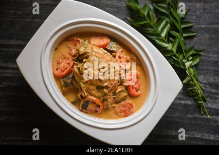 Draufsicht würzige Kerala Stil Fisch Curry Eintopf und Appam Fisch Molee Meen Moilee Indische Küche. Fischcurry mit Kokosmilch rote Chili, Curryblatt, Tomaten. Stockfoto