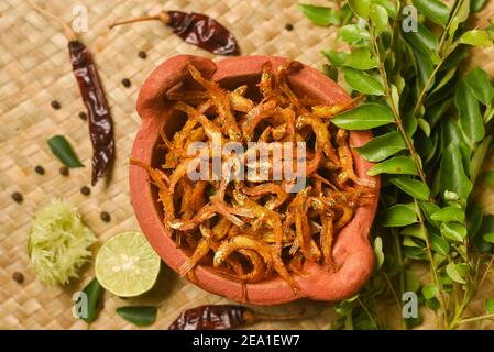 Draufsicht würzige heiße Sardellen Kerala Fisch Curry. Indisches Essen. Frau Hand machen Fisch braten mit roten Chili, Curryblatt, Kokosmilch. Asiatische Küche Stockfoto