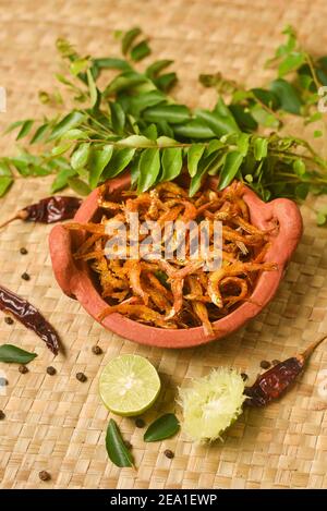 Draufsicht würzige heiße Sardellen Kerala Fisch Curry. Indisches Essen. Frau Hand machen Fisch braten mit roten Chili, Curryblatt, Kokosmilch. Asiatische Küche Stockfoto