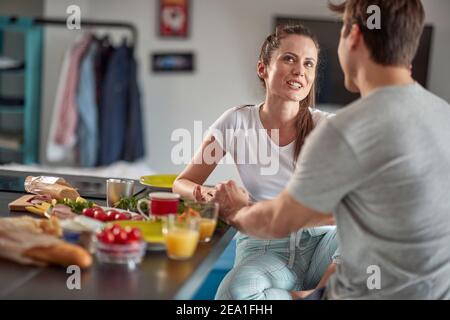 Ein junges verliebtes Paar, das beim Frühstück in einer fröhlichen Atmosphäre zu Hause einen netten Plausch hat. Paar, Liebe, Frühstück, zusammen Stockfoto
