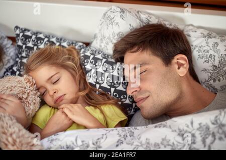 Papa und kleine Tochter schlafen an einem schönen Morgen zu Hause. Familie, Zuhause, zusammen Stockfoto