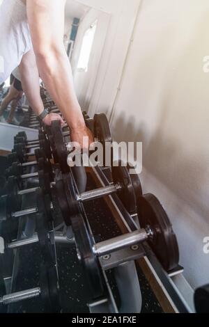 Hand ergreift eine Hantel, auf einer Hantelbank. Fitnessraum. Sportkonzept Stockfoto