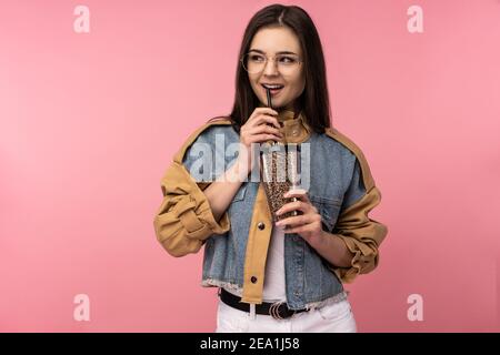 Foto von attraktiven Dame in Gläsern hält Tee Kaffee trinken, trägt lässige Jeans Jacke weiß Unterhemd isoliert rosa Farbe Hintergrund Stockfoto