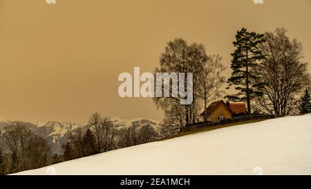 Winter Landschaft mit Sahara Sandwolke, Landschaft mit sandigen Wolken und verschneiten Bergen, Schneefeld und Wäldern. Säntis und Alpstein im Hintergrund Schnee Stockfoto