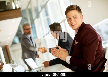 Hübscher junger Mann klatscht nach erfolgreichem Geschäftstreffen in die Hände Das moderne Büro Stockfoto