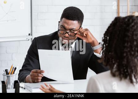 Strenge männliche HR-Manager Lesen Lebenslauf, Blick auf Job-Bewerber mit Verdacht während der Beschäftigung Interview in modernen Büro Stockfoto