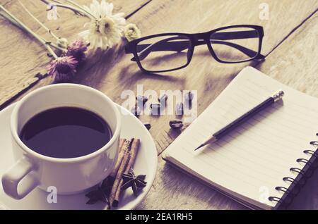 Kaffeetassen und Brillen legten am Morgen Blumen auf den Holzboden. Stockfoto