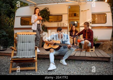 Freunde singen Lieder mit Gitarre, Picknick beim Camping Stockfoto