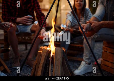 Freunde sitzen am Lagerfeuer am Abend Stockfoto