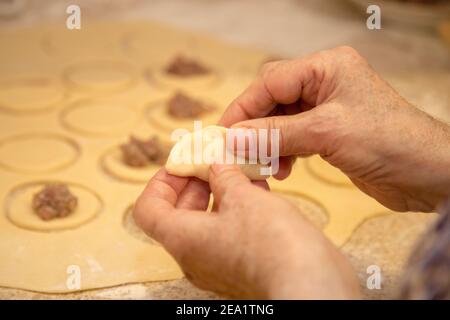 Die Hände der weißen älteren Frau machen hausgemachte Knödel aus der Nähe Stockfoto