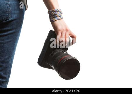 Mädchen hält in ihrer Hand eine DSLR-Kamera. Isoliert auf weißem Hintergrund. Rückansicht im Studio. An Jeans, Sweatshirt und Armband des Mädchens Stockfoto
