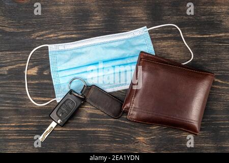 Draufsicht auf medizinische Maske, Schlüssel und Brieftasche auf einem Tisch platziert. Wesentliche Elemente während der Epidemie covid19. Stockfoto