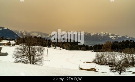 Winter Landschaft mit Sahara Sandwolke, Landschaft mit sandigen Wolken und verschneiten Bergen, Schneefeld und Wäldern. Säntis und Alpstein im Hintergrund Schnee Stockfoto