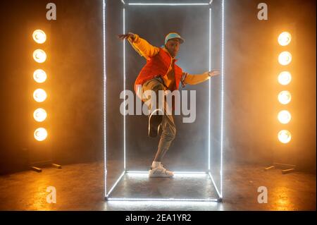 Stilvoller Rapper auf der Bühne mit beleuchtetem Würfel Stockfoto