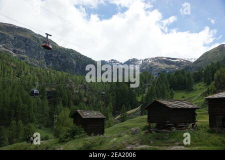 Schweizer Berghütten unter den Gondeln der Seilbahn. Stockfoto