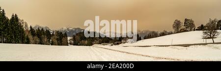 Winter Landschaft mit Sahara Sandwolke, Landschaft mit sandigen Wolken und verschneiten Bergen, Schneefeld und Wäldern. Säntis und Alpstein im Hintergrund Schnee Stockfoto