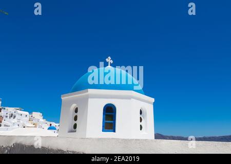 Santorini, Griechenland - 07. Juli 2017: Blaue Kuppel der Kirche aus nächster Nähe auf der Insel Santorini. Hintergrund weiße Häuser und blaues Meer. Stockfoto