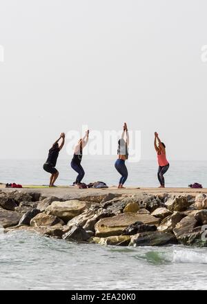 Eine Gruppe von Leuten, die Gymnastik auf einigen Felsen vor dem Meer in Fuengirola machen. Stockfoto