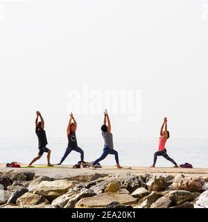 Eine Gruppe von Leuten, die Gymnastik auf einigen Felsen vor dem Meer in Fuengirola machen. Stockfoto