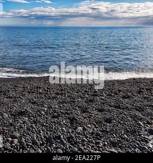 Schwarze Steine, die vom Meer umgeben sind, Lavakiesel am Strand von Djupalonsandur, Djupalonsandur, Hellnar, Halbinsel Snaefellsnes, Snaefellsnes, Vesturland Stockfoto