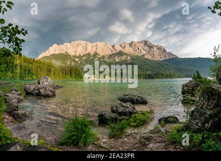 Felsen am Ufer, Eibsee See vor Zugspitzmassiv mit Zugspitze, dramatische Mammatenwolken, Wettersteingebirge, bei Grainau, Obere Stockfoto